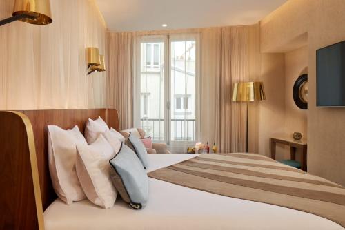 a hotel room with a large bed with pillows at Maison Albar - Le Pont-Neuf in Paris