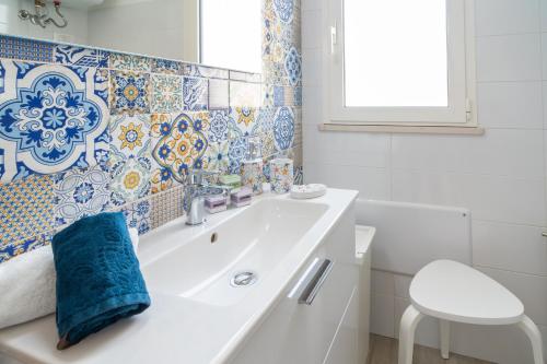 a bathroom with a white sink and blue and white tiles at Stella ventis in Marzamemi