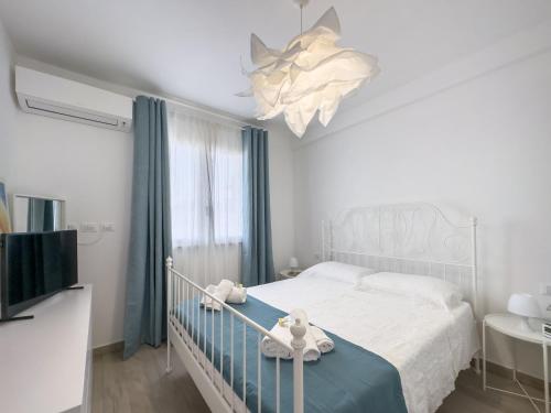 a white bedroom with a bed and a chandelier at Stella ventis in Marzamemi