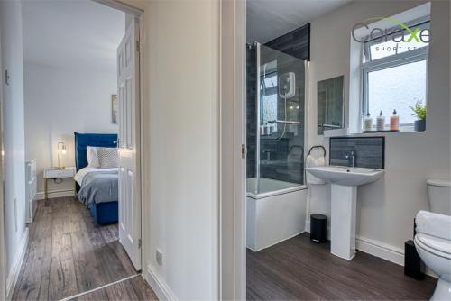 a bathroom with a sink and a toilet and a bed at 3 Bedroom Luxe Living for Contractors and Families by Coraxe Short Stays in Dudley