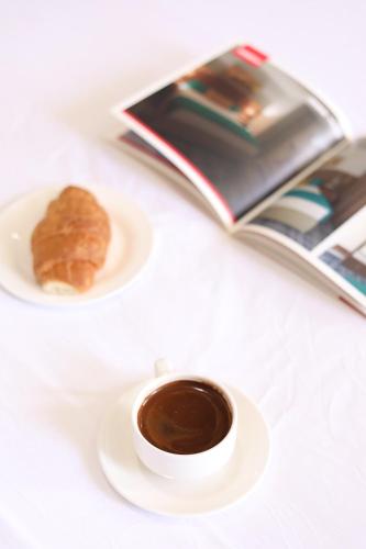 a cup of coffee and a pastry on a plate with a book at The Castle Hotel in Amman