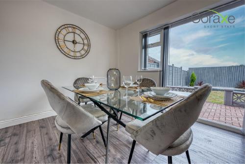 a dining room with a glass table and chairs and a clock at 3 Bedroom Blissful Living for Contractors and Families by Coraxe Short Stays in Dudley