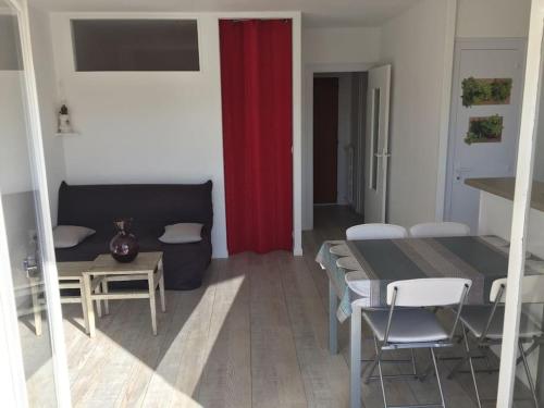 a living room with a table and a red curtain at Beau 2 pièces proche plage et commerces in Le Pouliguen