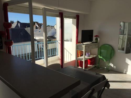 ein Wohnzimmer mit einem Tisch und Blick auf einen Balkon in der Unterkunft Beau 2 pièces proche plage et commerces in Le Pouliguen