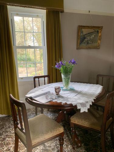 a dining room table with a vase of flowers on it at Tullyard House in Tullaghoge