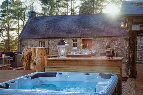 a hot tub on a deck next to a house at Crofts of Cairngrom in Nethy Bridge