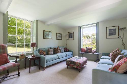 a living room with two blue couches and two windows at Almsbury Farmhouse in Winchcombe