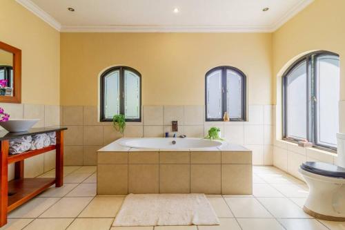 a bathroom with a tub and a toilet and windows at Lovely Family home in Bryanston in Johannesburg