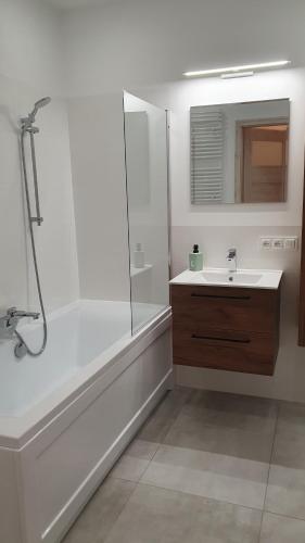 a white bathroom with a shower and a sink at Pokoje Oszmiańska in Warsaw