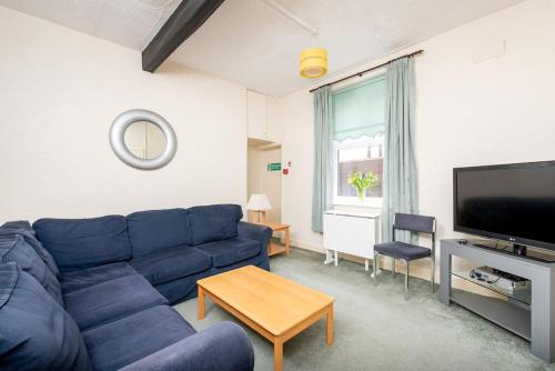 a living room with a blue couch and a tv at Sandpiper Holiday Apartments in Blackpool