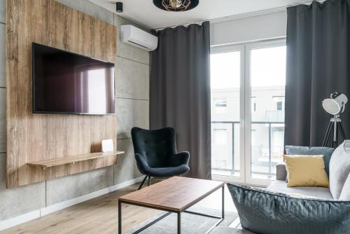 a living room with a couch and a chair and a tv at RentPlanet - Kępa Mieszczańska in Wrocław