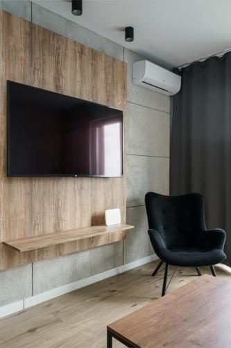 a black chair and a television on a wall at RentPlanet - Kępa Mieszczańska in Wrocław