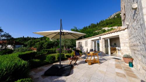 une terrasse avec un parasol, une table et des chaises dans l'établissement Charming Sea View "Villa Divine" - 2min from the sea, à Lopud