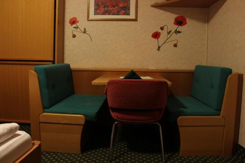 a room with two chairs and a table and flowers on the wall at Hotel Villa Emilia in Ortisei