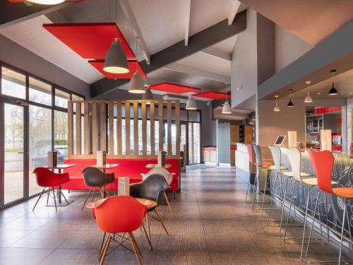 un restaurante con mesas y sillas rojas y ventanas en ibis Amboise en Amboise