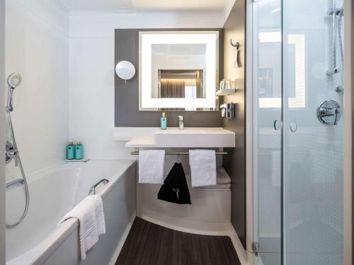 uma casa de banho com uma banheira, um lavatório e um espelho. em Novotel Suites Wien City Donau em Viena