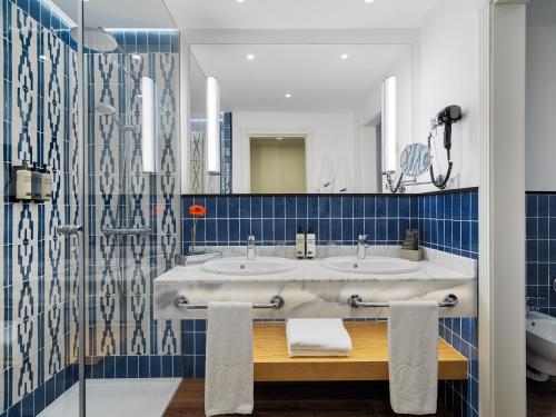 a bathroom with two sinks and a mirror at H10 Playa Meloneras Palace in Meloneras