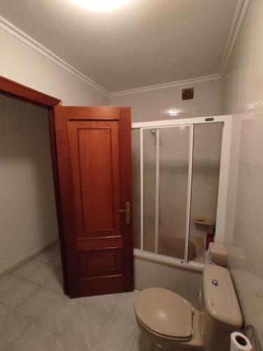 La salle de bains est pourvue de toilettes et d'une porte en bois. dans l'établissement Piso 4 habitaciones Valdoviño cerca de la Playa, à Valdoviño