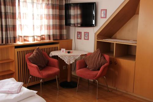 a room with two chairs and a table with a table at Hotel Villa Emilia in Ortisei