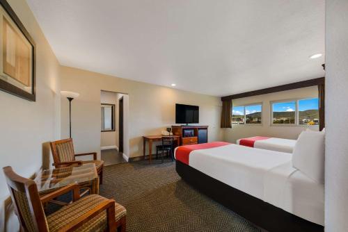 a hotel room with two beds and a desk at Rodeway Inn South San Francisco Airport in South San Francisco