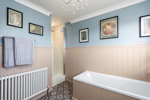 a bathroom with blue walls and a bath tub at The Laurel Cottage in Doncaster