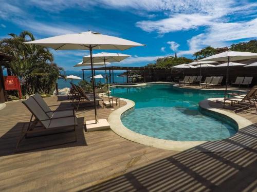 布希奧斯的住宿－Hotel La Forêt & Beach Club，甲板上配有椅子和遮阳伞的游泳池