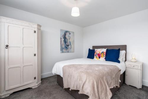 a white bedroom with a bed with blue pillows at The Laurel Cottage in Doncaster