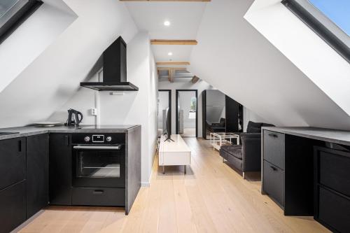 cocina con armarios negros y sala de estar. en Stay Bryggen - Serviced apartments in the city center, en Bergen