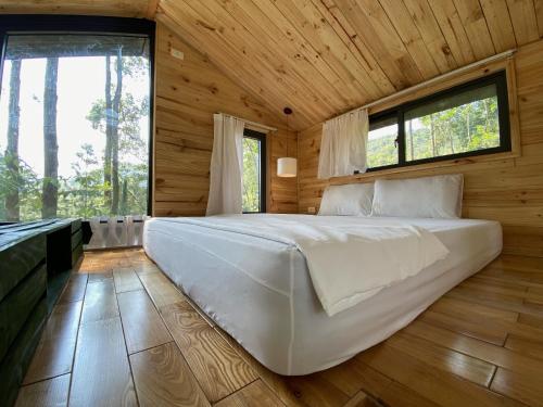 ein großes weißes Bett in einem Holzzimmer mit Fenstern in der Unterkunft Sausau Garden, a pefect retreat for relaxing, close to Noi Bai airport in Sóc Sơn