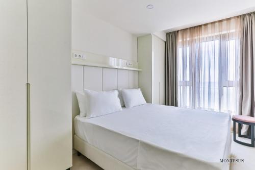 a white bedroom with a large bed and a window at Montesun RAF Apartments in Budva