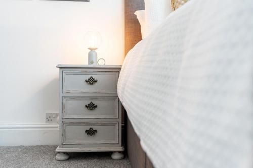 a bedroom with a dresser with a white bedspread at The Laurel Cottage in Doncaster