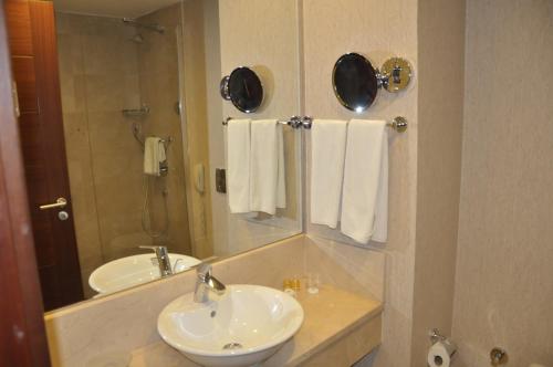 a bathroom with a sink and a mirror and towels at Happy Inn Gebze Hotel in Kocaeli