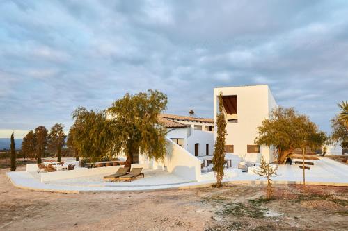 Uma casa branca com um banco à frente. em Finca las Calmas boutique hotel & retreats em Moraleda de Zafayona