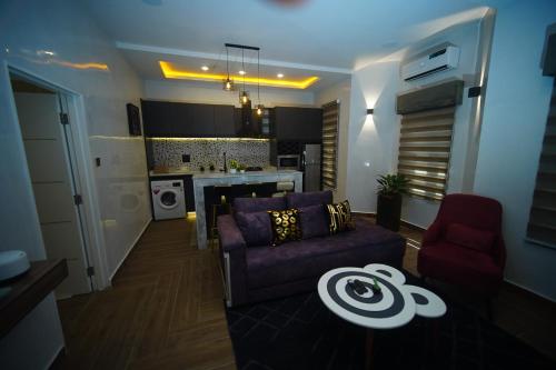 a living room with a purple couch and a kitchen at Hortencia by Durudove Apartments in Kubwa