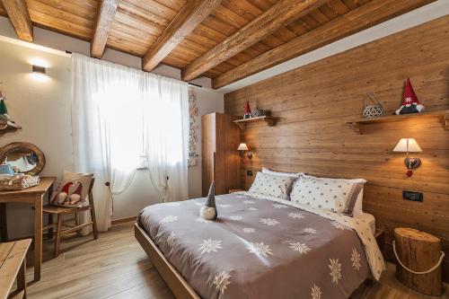 1 dormitorio con 1 cama y pared de madera en Malga Laben, en Velo Veronese