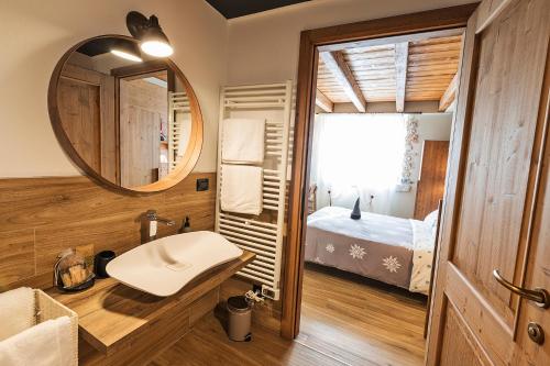 ein Bad mit einem Waschbecken, einem Spiegel und einem Bett in der Unterkunft Malga Laben in Velo Veronese