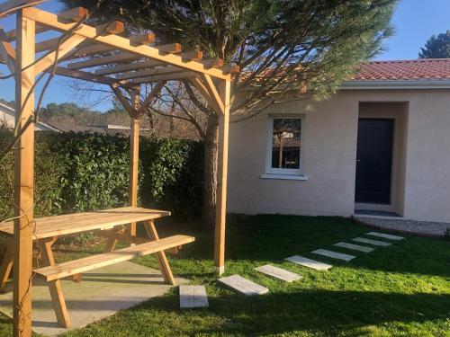 - une table de pique-nique en bois sous une pergola en bois dans l'établissement Chambre d'Hôtes Les Bacquerins, à Sainte-Hélène