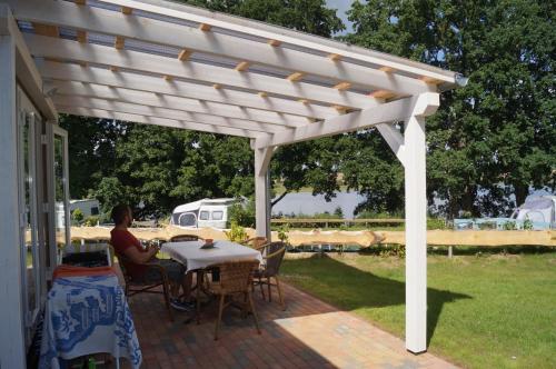 a white pergola on a patio with a table at Mobilheim und Blockhaus mit Seeblick in Sternberg