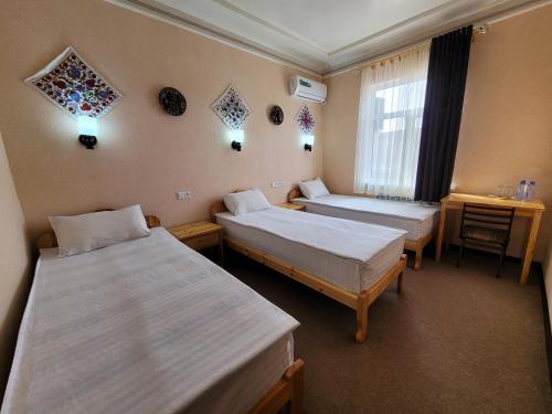 ヒヴァにあるイスラム ホジャのベッド2台と窓が備わるホテルルームです。