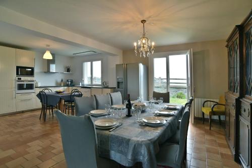 une salle à manger avec une table et une cuisine dans l'établissement Côté Plage - Maison pour 12 vue mer, à Saint-Cast-le-Guildo