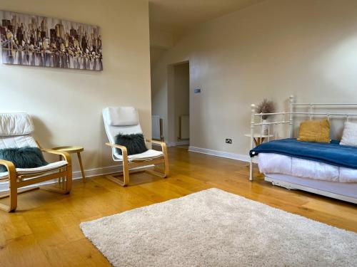 Habitación con 2 sillas, 1 cama y 1 alfombra en City Link - Mapperley Park Penthouse - Free parking,tram&bus,HSwifi,7ppl by KP, en Nottingham