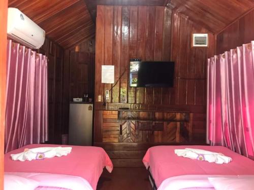 een slaapkamer met 2 bedden met roze lakens en een tv bij กอบสุข รีสอร์ท 2 k11 in Ban Ton Liang