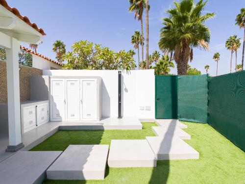 a backyard with a white fence and grass at Aquarium Bungalow private jacuzzi, 3 bedrooms, AC and Bikes in Maspalomas