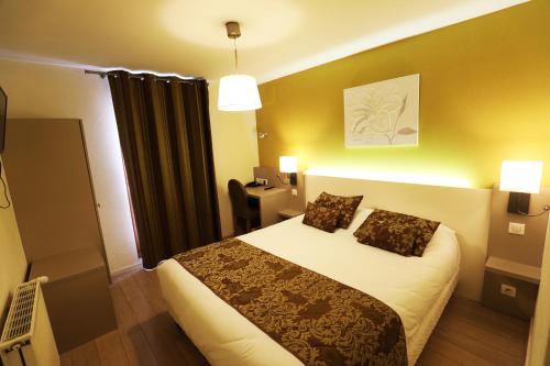 a hotel room with a bed with two pillows at Logis Le Bourguignon in Bèze
