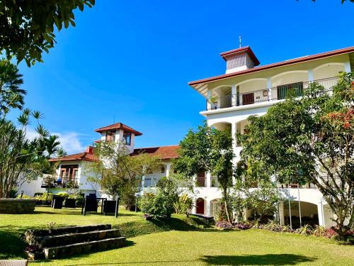 ein großes weißes Gebäude mit Bäumen im Vordergrund in der Unterkunft Elegant Hotel in Kandy