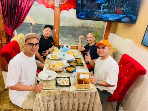 a group of men sitting at a table eating food at Miracle Gallery Hotel in Makkasan