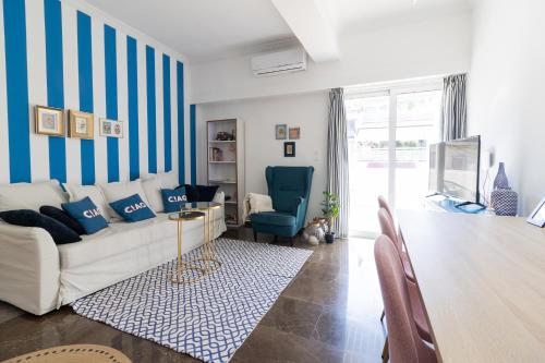 a living room with a white couch and blue striped walls at Retropolitan Living Patras in Patra