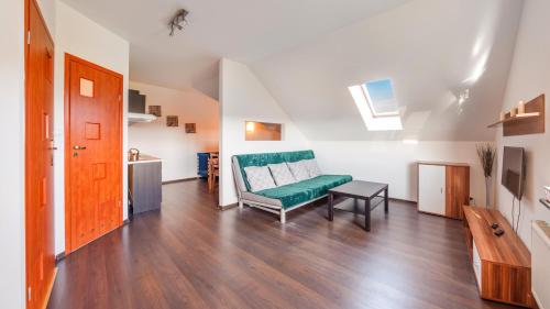 a living room with a green couch and a table at Apartamenty Sun & Snow Rzemieslnicza in Władysławowo