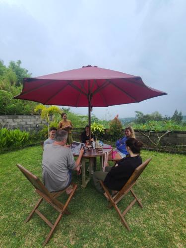 a group of people sitting at a table under an umbrella at Volcano Lake View in Kintamani