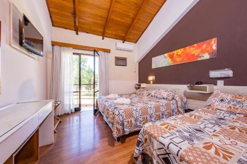 a hotel room with two beds and a balcony at Costanera Hotel in Villa Carlos Paz